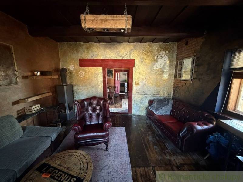 Rustikales Wohnzimmer in einem Einfamilienhaus mit Ledersesseln und einem Boden in Holzoptik.