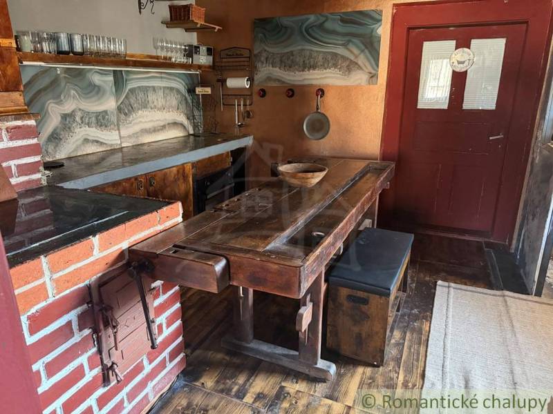 Rustikale Küche in einem Einfamilienhaus mit Backsteindetails und einem Boden in Holzoptik.