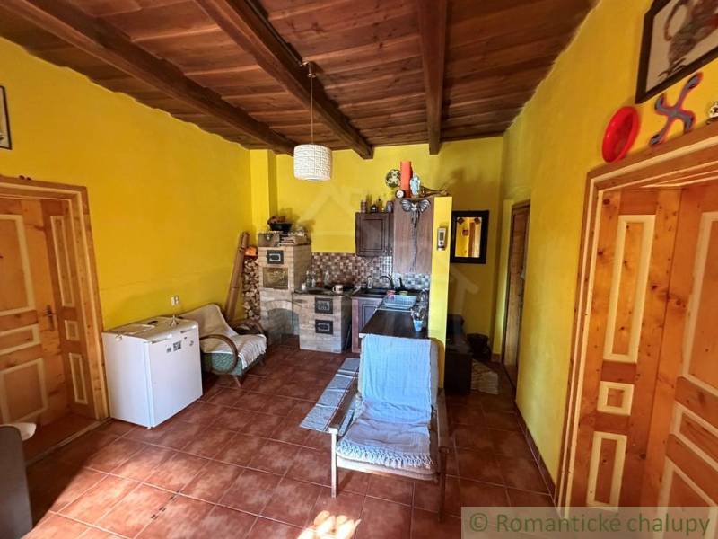 Innenraum eines Einfamilienhauses mit Holzbalkendecke und gelben Wänden.