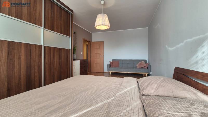 Schlafzimmer in einer 2-Zimmer-Wohnung mit Sofa, Kleiderschrank und Holzboden.