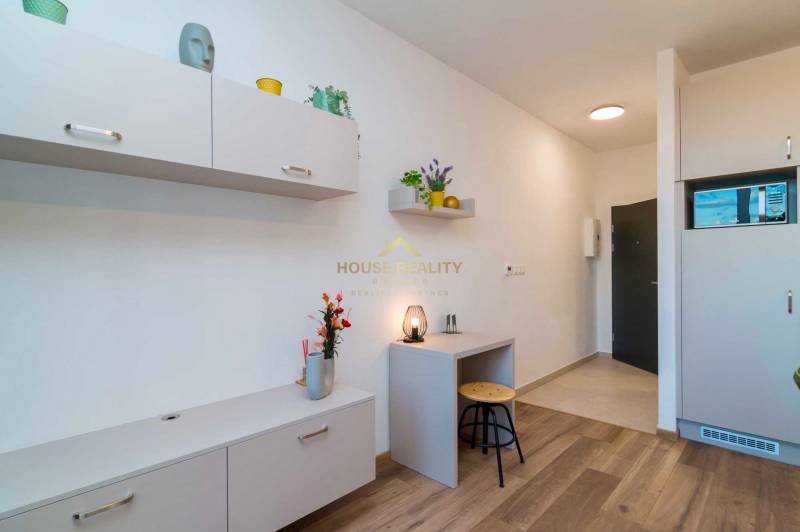 Innenraum einer Einzimmerwohnung mit hellen Möbeln und einem Boden in Holzoptik.