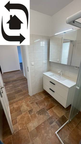 Ein Badezimmer in einem Einfamilienhaus mit einem Boden in Holzoptik und einer Duschkabine.