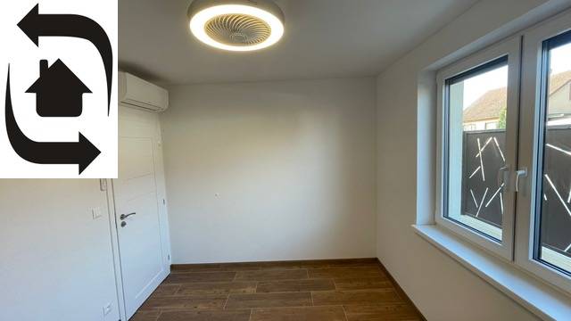 Ein Raum in einem Einfamilienhaus mit einem Boden in Holzoptik, Klimaanlage und Fenster.