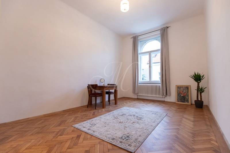 Ein Zimmer in einer 3-Zimmer-Wohnung mit einem Holzboden, einem Tisch und einer Pflanze.