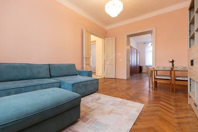 Ein Zimmer in einer 3-Zimmer-Wohnung mit einem blauen Sofa, einem Holzboden-Dekor und einem Essbereich.