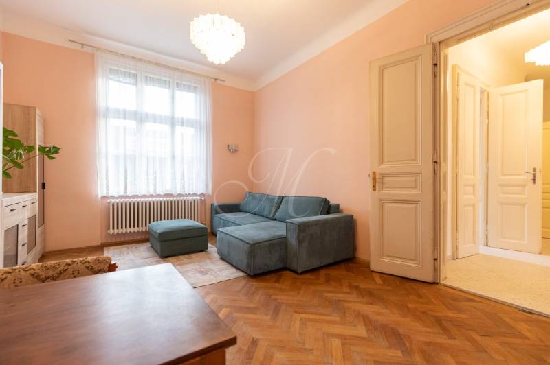 Helles Wohnzimmer mit Sofa, Kronleuchter und Holzboden in einer 3-Zimmer-Wohnung.