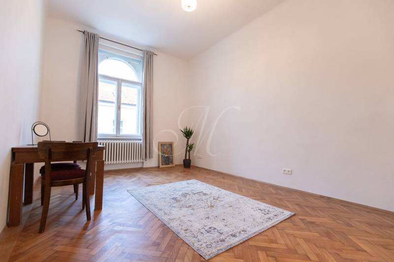 Ein Zimmer in einer 3-Zimmer-Wohnung mit einem Boden in Holzoptik, einem Teppich und einem Tisch.