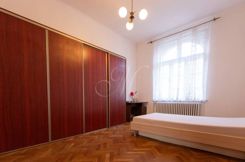 Schlafzimmer mit Bett, Boden mit Holzdekor, großer Schrank in einer 3-Zimmer-Wohnung.