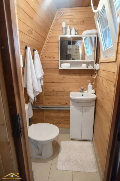 Badezimmer in einer Hütte mit Holzdekor an den Wänden und Grundausstattung.