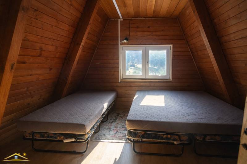 Dachbodenraum in einer Hütte mit zwei Betten und einem Boden mit Holzdekor.
