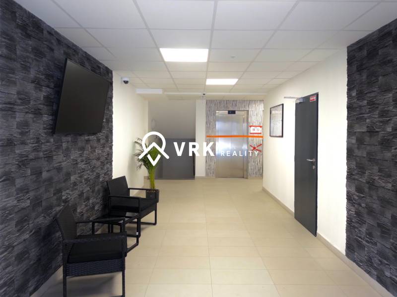 Flur in einer 3-Zimmer-Wohnung mit Fernseher an der Wand und Aufzug im Hintergrund.