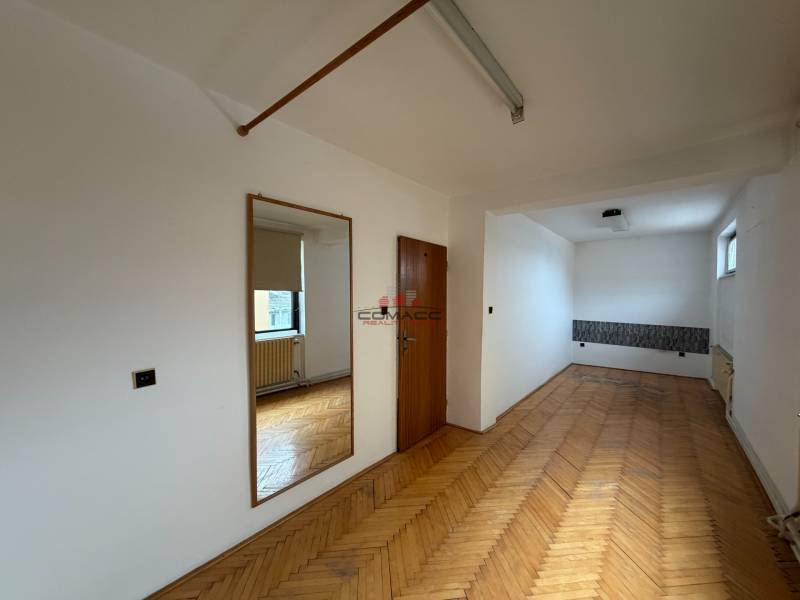 Ein Zimmer in einem Einfamilienhaus mit einem Boden in Holzoptik, einem Spiegel und einem Fenster.