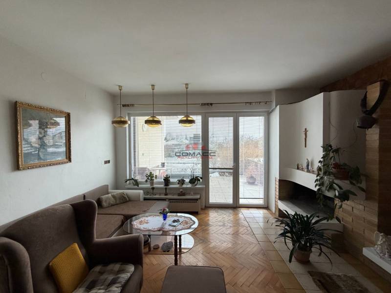 Wohnzimmer in einem Einfamilienhaus mit Kamin, Sofa und Boden in Holzoptik.