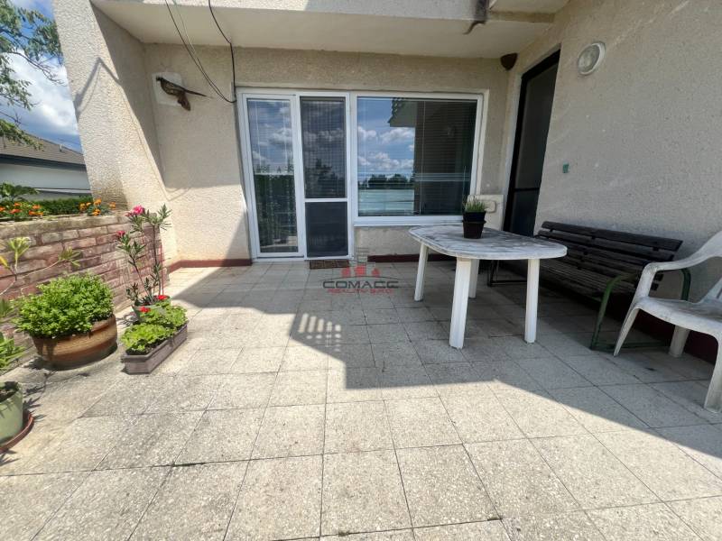 Die Terrasse des Einfamilienhauses in der Tálová-Straße in Veľké Orvište mit einem Plastiktisch und Blumen.