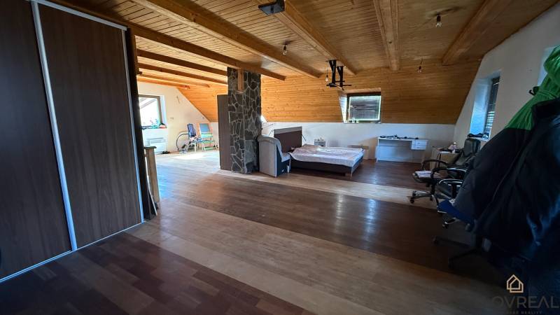 Dachzimmer mit Bett, Schrank und Holzboden in einem Einfamilienhaus.