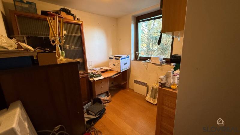 Ein Zimmer in einem Einfamilienhaus mit Einrichtung und einem Boden in Holzoptik.