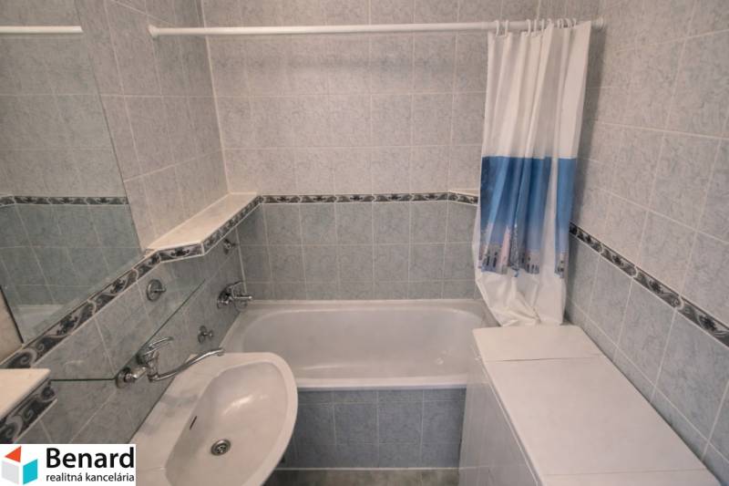 Badezimmer mit Badewanne und Waschbecken in einer 2-Zimmer-Wohnung, geflieste Wände.