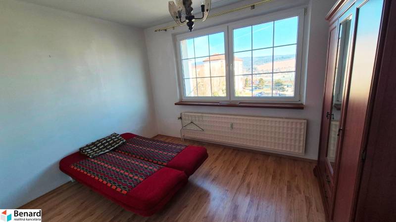 Schlafzimmer mit Bett, Schrank und Boden mit Holzdekor in einer 2-Zimmer-Wohnung.