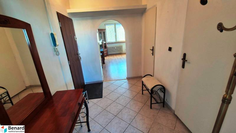 Flur mit einem Bogenübergang in einer 2-Zimmer-Wohnung, Boden mit Holzdekor, Spiegel, Bank.