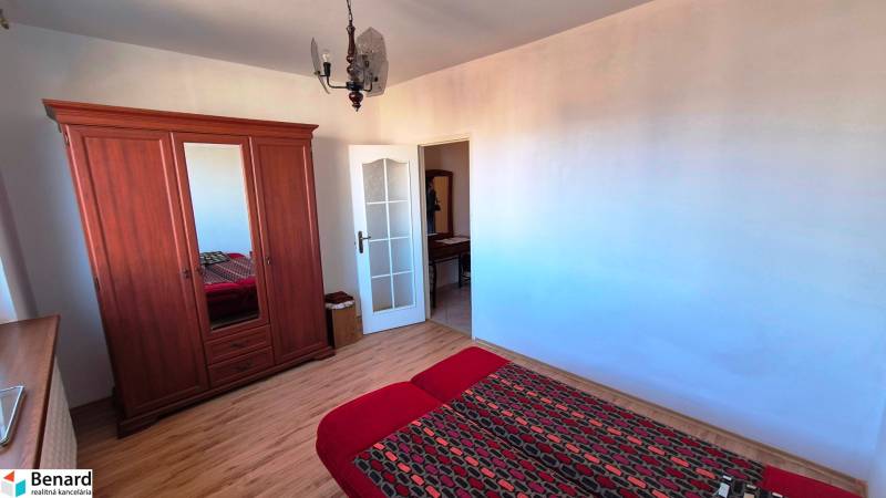 Schlafzimmer in einer 2-Zimmer-Wohnung mit Holzboden, Kleiderschrank und Bett.