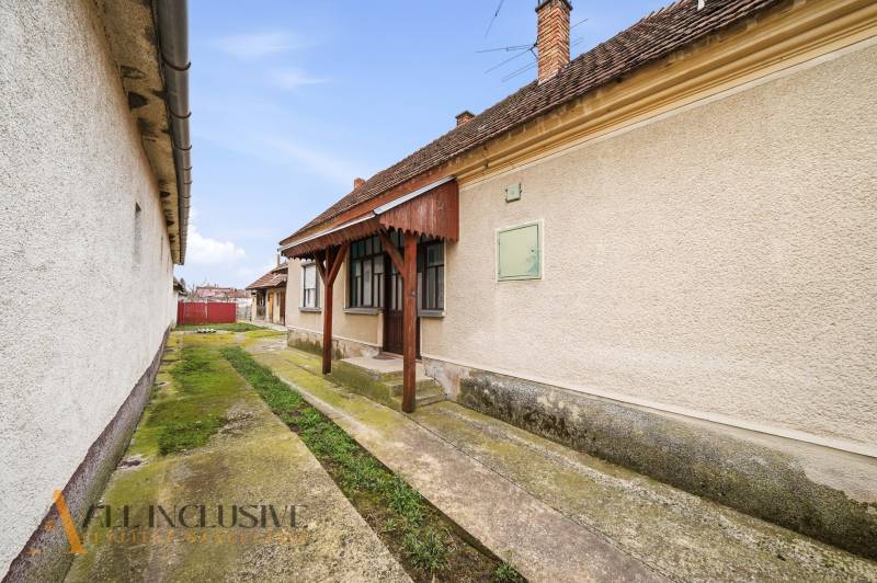 Ein Einfamilienhaus in Topoľníky mit gepflegter Fassade, Veranda und Betonweg.