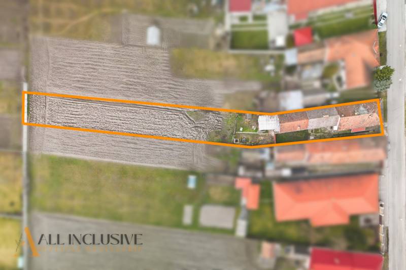 Ein Einfamilienhaus in Topoľníky mit Garten im Rahmen, sichtbar sind landwirtschaftliche Felder und Gebäude.