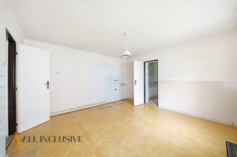 Ein geräumiges Zimmer in einem Einfamilienhaus mit einem Holzboden und einfacher Beleuchtung.