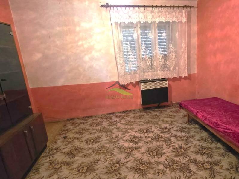 Ein Zimmer in einem Einfamilienhaus mit Teppich, Bett und Schrank, Vorhang am Fenster.