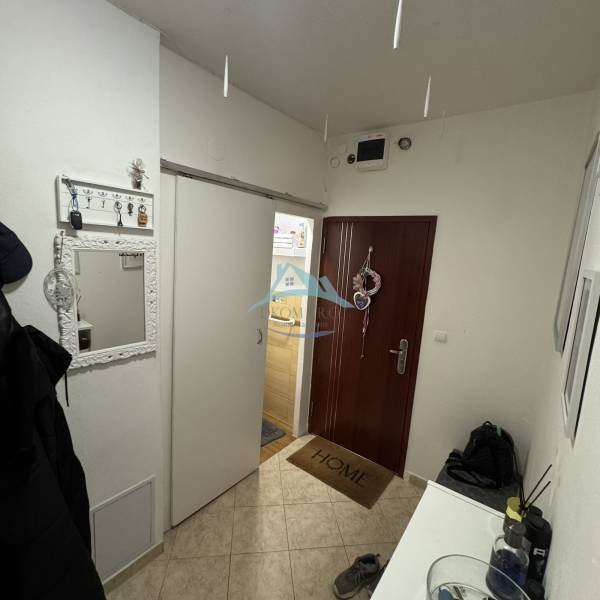 Diele einer 3-Zimmer-Wohnung mit Kleiderhaken, Spiegel und Eingangstür.