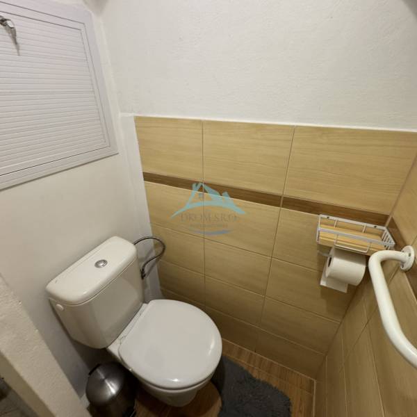 Badezimmer in einer 3-Zimmer-Wohnung mit Toilette und Fliesen in Holzoptik.