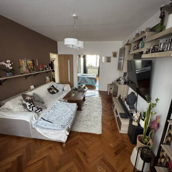 Wohnzimmer mit Sofa, Tisch und Boden in Holzoptik in einer 3-Zimmer-Wohnung.