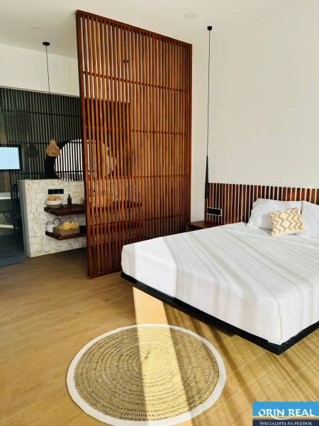 Schlafzimmer in einem Einfamilienhaus mit Holzboden, Holzwand und rundem Teppich.