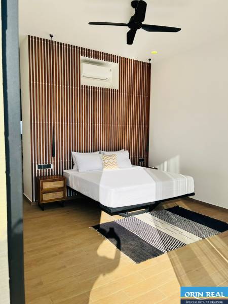 Schlafzimmer in einem Einfamilienhaus mit gemusterter Wand, Ventilator, Teppich und Boden in Holzoptik.