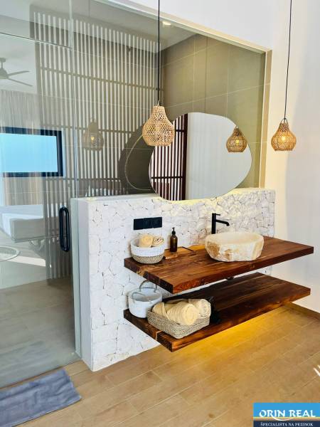 Badezimmer im Einfamilienhaus mit Waschbecken auf einem Holzregal und Boden mit Holzdekor.