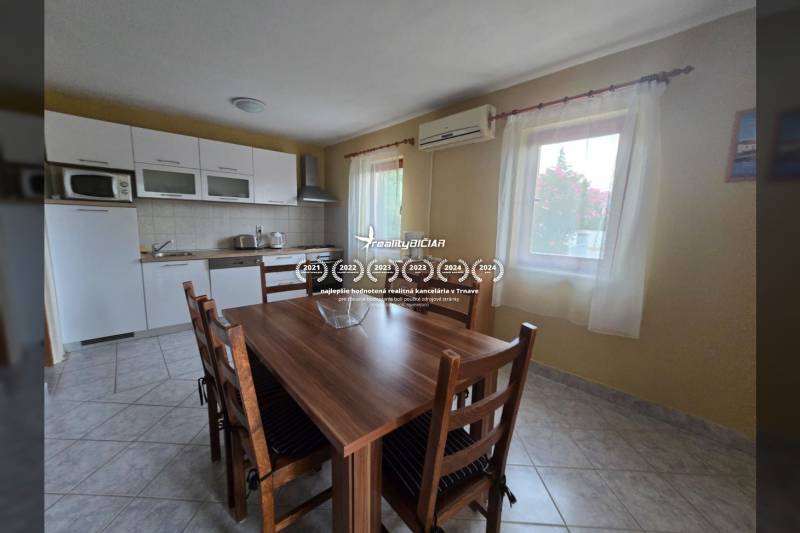 Küche in einer besonderen Immobilie mit Esstisch, weißen Schränken und Keramikfliesen.