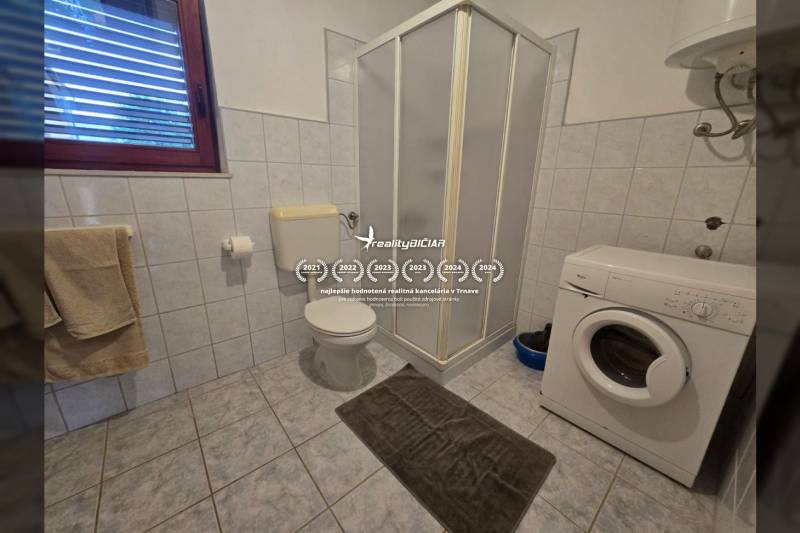 Badezimmer mit Dusche, Waschmaschine und Toilette, Besondere Immobilien.