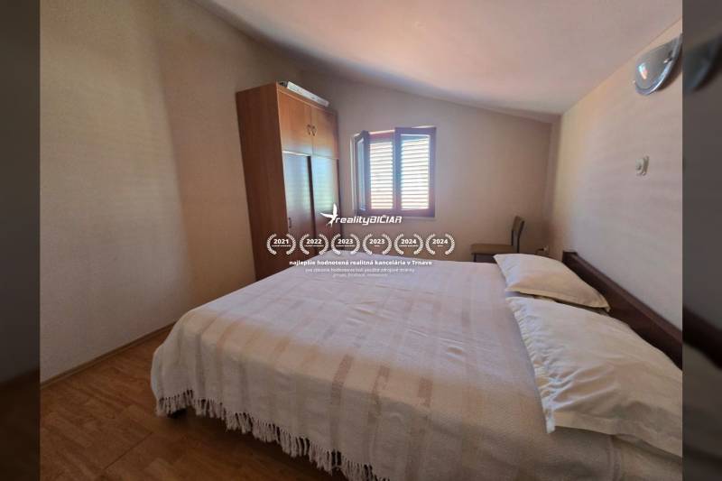 Schlafzimmer mit Schrank, Bett und Fenster, Boden mit Holzdekor, Besondere Immobilien.