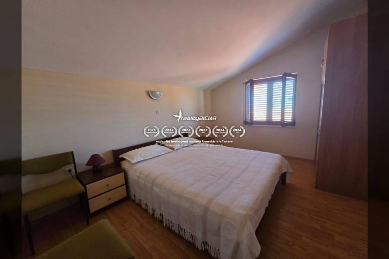 Ein Schlafzimmer mit Licht, das durch das Fenster fällt, einem Bett und einem Boden mit Holzdekor.