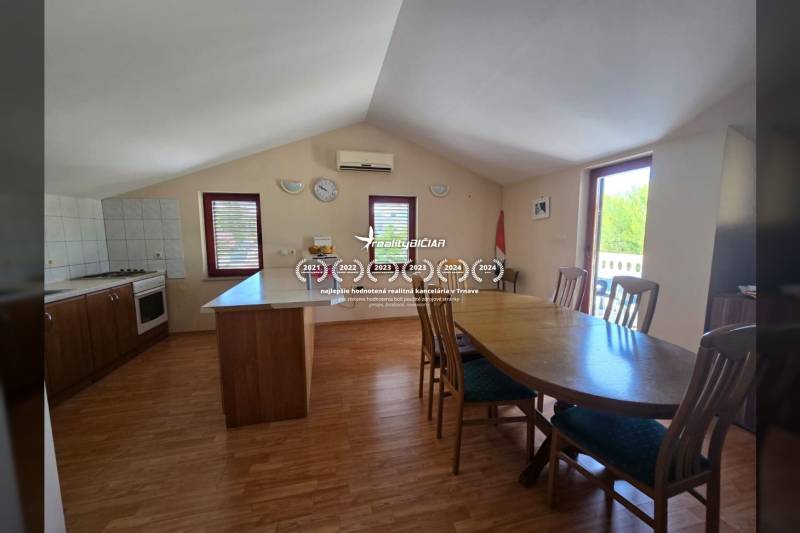 Esszimmer und Küche mit hellen Wänden, Holzboden und Möbeln.