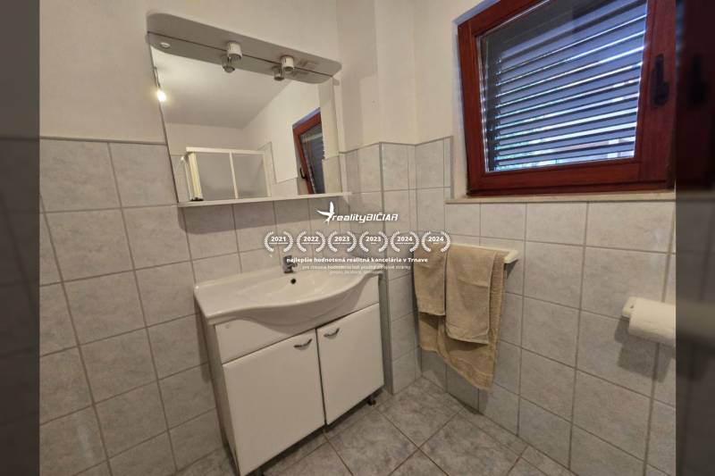 Badezimmer mit hellen Fliesen, Spiegel und Waschtischunterschrank, Besondere Immobilien.