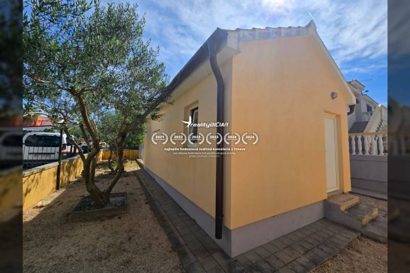 Das gelbe Haus mit Treppen und Bäumen im Garten in der Mulo-Straße in der Stadt Vrsi.