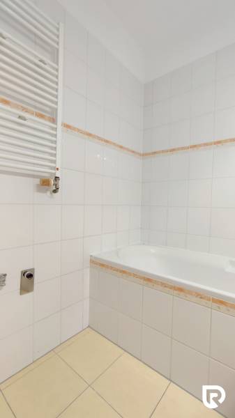 Badezimmer mit Badewanne und weißen Fliesen in einer 2-Zimmer-Wohnung.