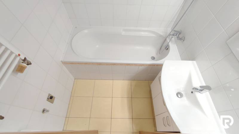 Badezimmer in einer 2-Zimmer-Wohnung mit Badewanne, Waschbecken und weißen Fliesen.