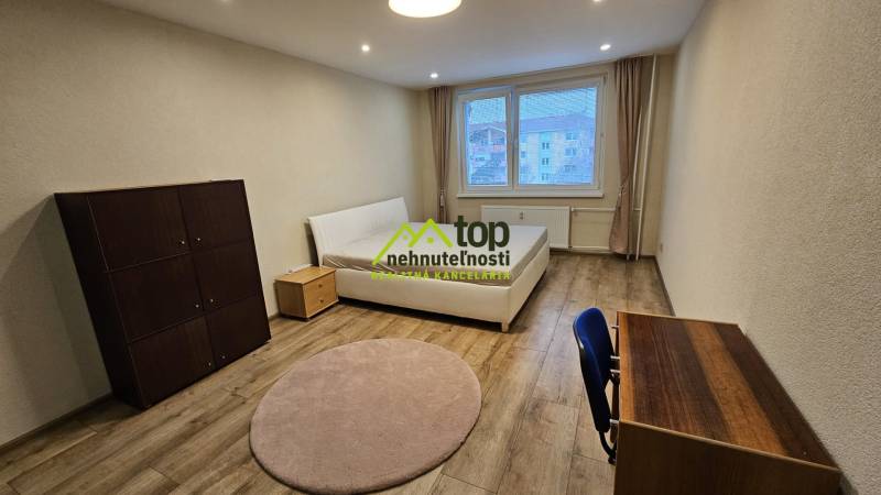 Helles Zimmer in einer 2-Zimmer-Wohnung mit Bett und Möbeln, Boden mit Holzdekor.