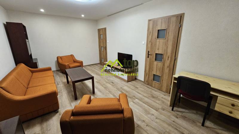 Wohnzimmer in einer Zweizimmerwohnung mit orangen Möbeln und einem Boden in Holzoptik.