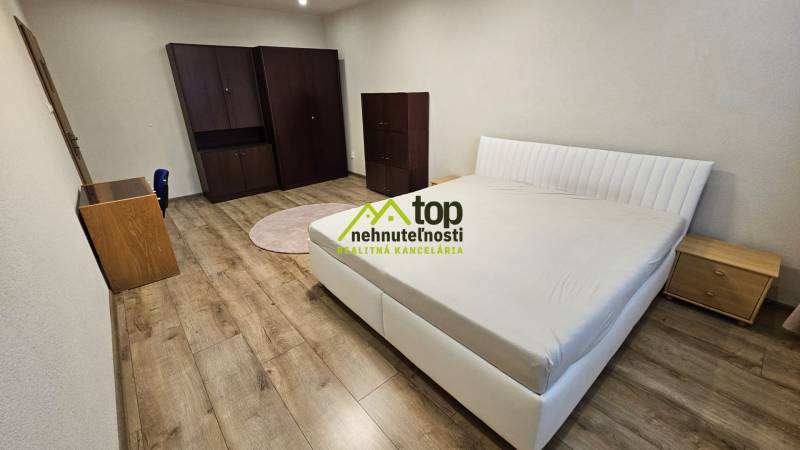 Schlafzimmer in einer 2-Zimmer-Wohnung mit Bett, Schrank und Boden in Holzoptik.