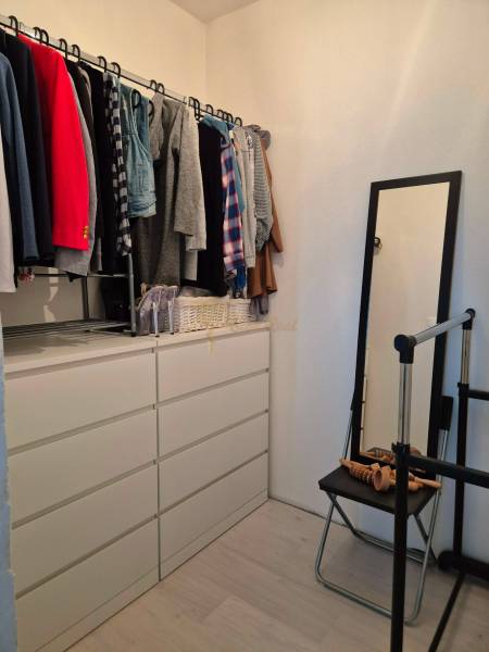 Garderobe in einer 3-Zimmer-Wohnung mit Kleiderbügeln und Kommode, Boden mit Holzdekor.