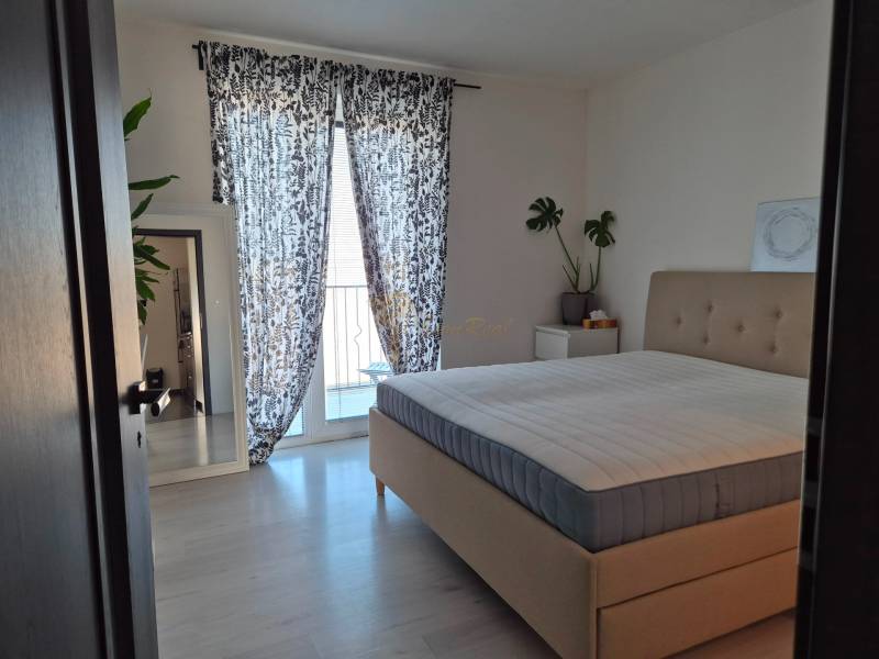 Schlafzimmer mit großem Bett, Pflanzen, Spiegel und Vorhängen in einer 3-Zimmer-Wohnung.