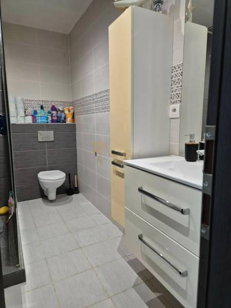 Badezimmer in einer 3-Zimmer-Wohnung mit hängendem WC, Waschbecken, Schrank und hellen Fliesen.