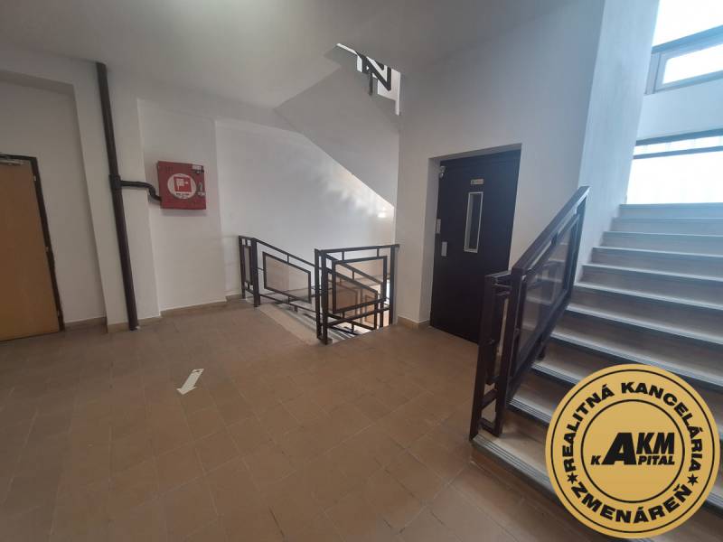 Treppenhaus in Büros mit Fliesen und Aufzug. An der Wand ein Notfallkasten.